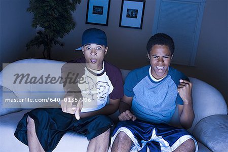 High angle view of a young man and a teenage boy sitting on a couch watching television