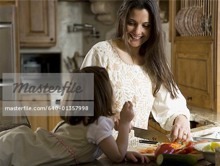 Fille dans la cuisine avec la femme de hacher les légumes