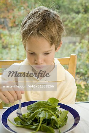 Gros plan d'un garçon, manger des épinards à la fourchette