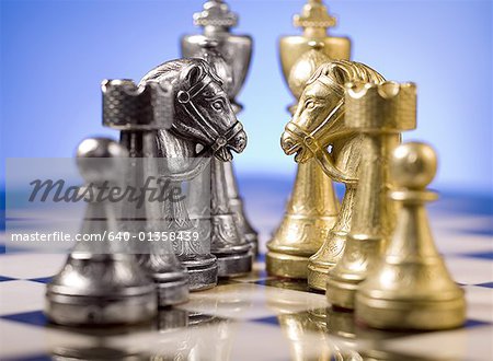 Close-up of chess pieces on a chessboard facing each other