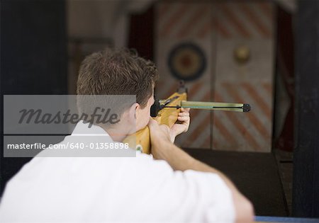 Rear view of a young man target shooting