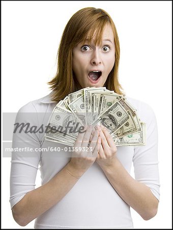 Portrait of a young woman holding fanned out dollar bills