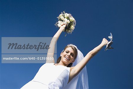 Portrait of a bride holding a bouquet of flowers and a pair of sandals