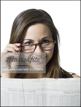 Portrait d'une jeune femme lisant un journal et de la lecture sur ses lunettes