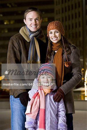 Homme à la femme et la jeune fille debout à l'extérieur en hiver souriant