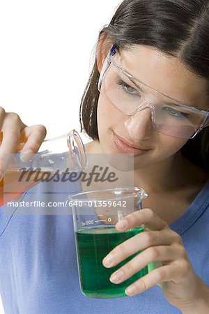 Close-up of a female technician pouring liquid from a conical flask into a beaker