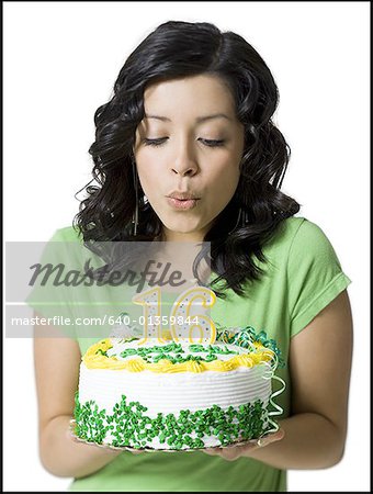 Close-up of a teenage girl blowing out candles on her birthday cake