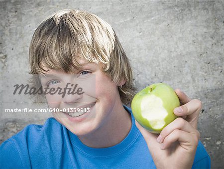 Portrait of a teenage Boy hält einen Apfel und fröhlich auf der Suche
