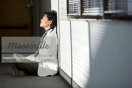 Profile of a female doctor sitting on the floor with her eyes closed