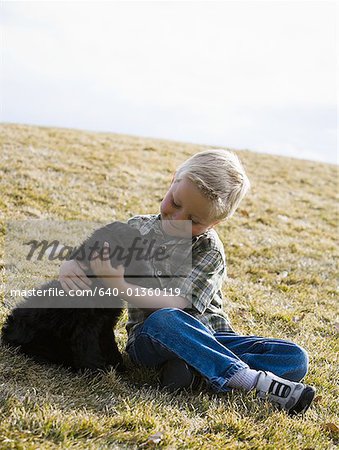 Boy sitting on grass outdoors with puppy