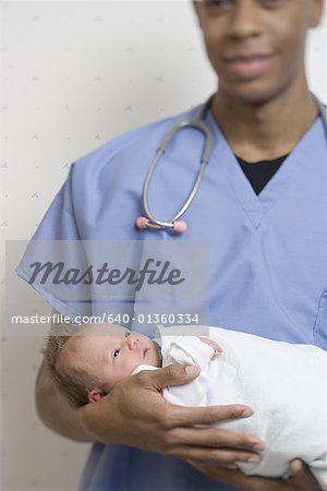 Male doctor carrying a new born baby
