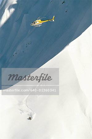 Helicopter and snowboarder on mountain in winter