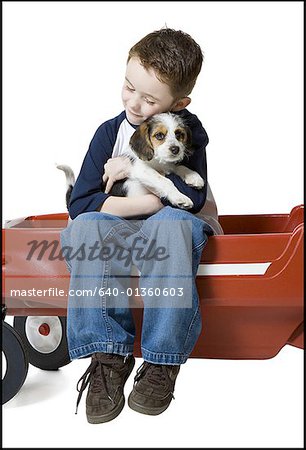 Close-up of a boy sitting on a wagon hugging a puppy