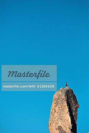 Low angle view of a two people on the peak of a rock formation