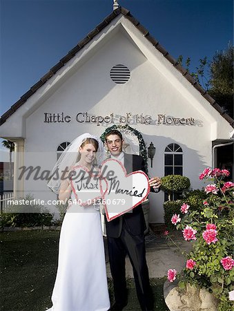 Portrait of a newlywed couple smiling together in front of a chapel