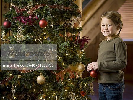 Girl with Christmas bauble and Christmas tree