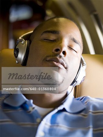 Gros plan d'un homme à l'écoute de musique sur le casque dans un avion