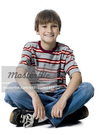 Portrait d'un garçon assis avec les jambes croisées