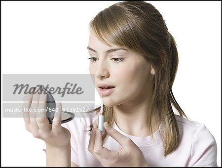 Close-up of a girl applying lipstick on her lips