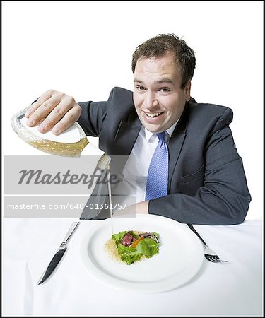 Gros plan d'un jeune homme, verser la vinaigrette sur sa salade
