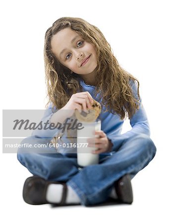 Portrait eines Mädchens, das Eintauchen eines Cookies in einem Glas Milch