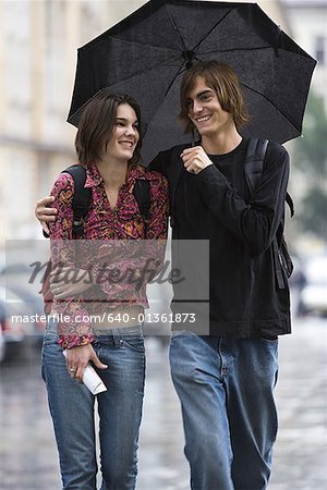 Young man walking with a young woman under an umbrella