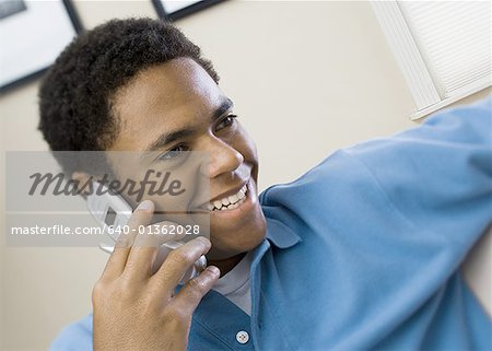 Gros plan d'un garçon de parler sur un téléphone mobile souriant