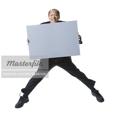 Portrait of a businessman holding a blank sign and jumping