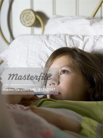 Girl in bed with thermometer