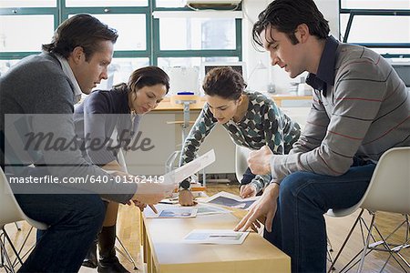 Four people looking at ad layouts
