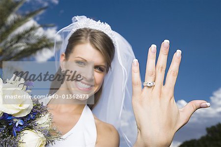 Portrait d'une jeune mariée montrant sa bague de mariage et souriant