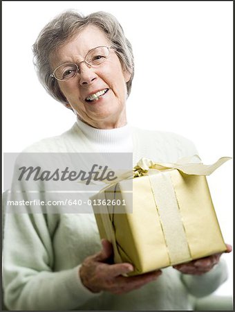 Portrait d'une femme senior tenant un cadeau et souriant