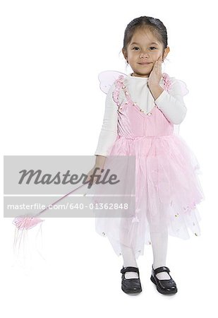 Portrait d'une jeune fille habillé dans un costume de fée tenant une baguette magique