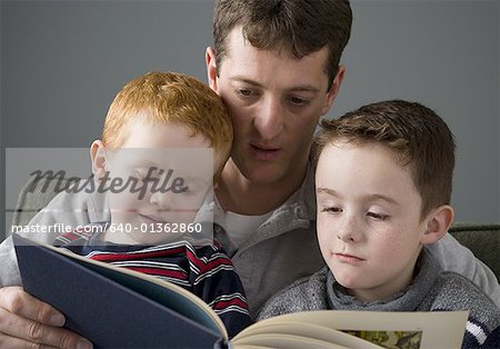 Nahaufnahme eines Vaters mit seinen beiden Söhnen ein Buch zu lesen.