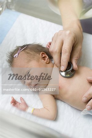 High angle view of a doctor's hands examining a newborn baby with a stethoscope