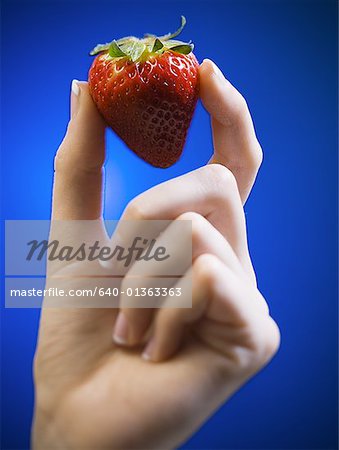 Close-up of a woman's hand holding a strawberry