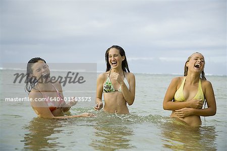 Drei Teenager im Meer stehen und lachen