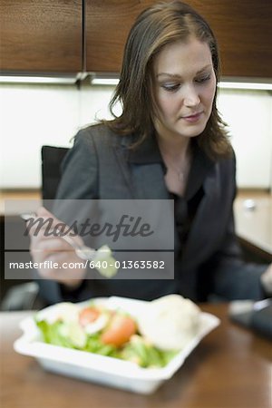 Femme d'affaires, manger une salade à son pupitre