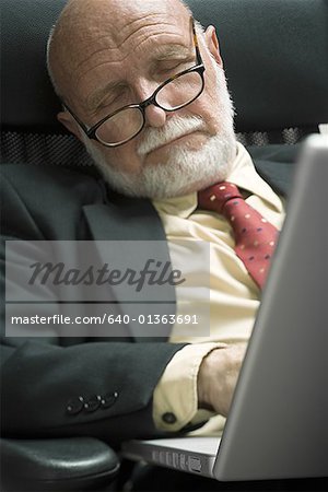 Close-up of a businessman sleeping in front of a laptop