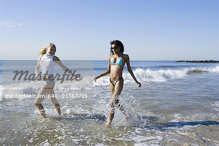 Two young women running in the water on the beach