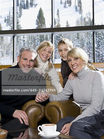 Portrait of an adult couple sitting on armchairs with their two children