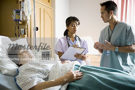 Doctor and nurse talking with sleeping female patient in hospital bed