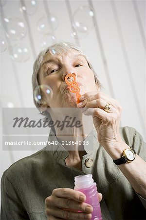 Porträt einer alten Frau bläst Seifenblasen mit einem Seifenblasen