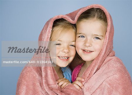 Portrait de deux jeunes filles sous une couverture et souriant