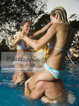 Two couples horsing around in a swimming pool