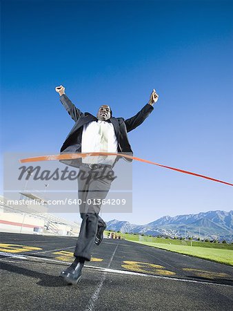 Businessman running and crossing finish line