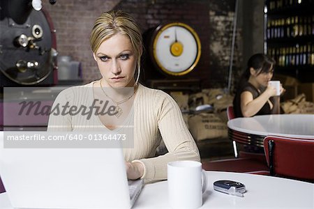 Jeune femme travaillant sur un ordinateur portable dans un café