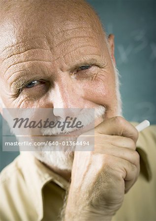 Portrait d'un professeur masculin senior tenant la craie