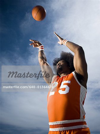 Basketball player with an afro in orange uniform taking shot