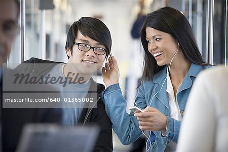 Woman sharing her MP3 player with a young man on a commuter train
